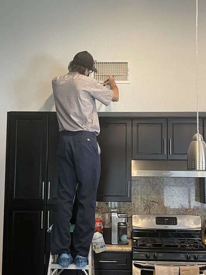 Technician inspecting an air vent during HVAC service in Sandersville